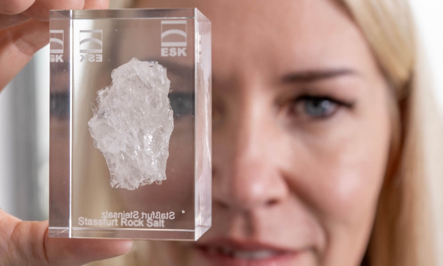 Andrea Wobito hält ein Acrylglas, in dem ein Stück Steinsalz aus Staßfurt eingegossen ist, in die Kamera