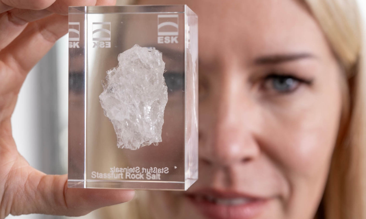 Andrea Wobito hält ein Acrylglas, in dem ein Stück Steinsalz aus Staßfurt eingegossen ist, in die Kamera