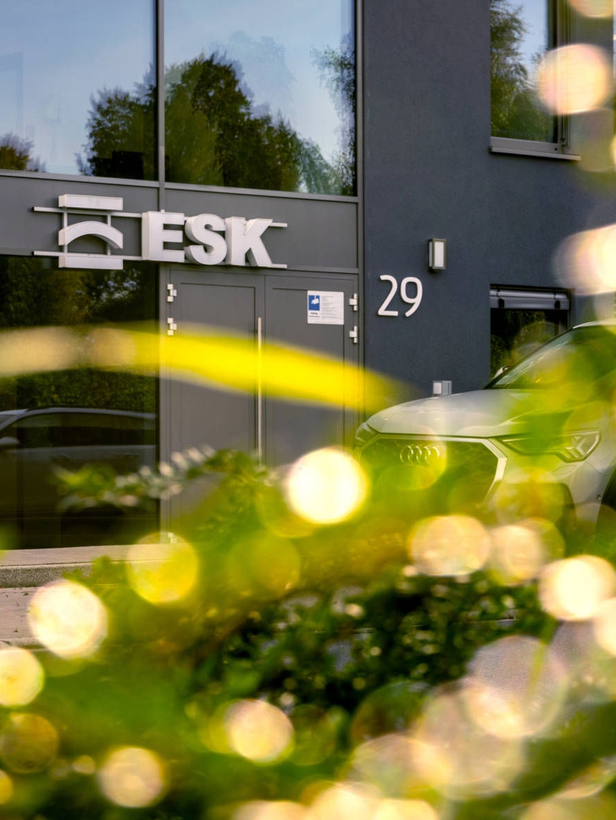 Eingang des anthrazit-farbigen Bürogebäudes der ESK GmbH in Holzwickede mit reflektierendem Licht im Vordergrund