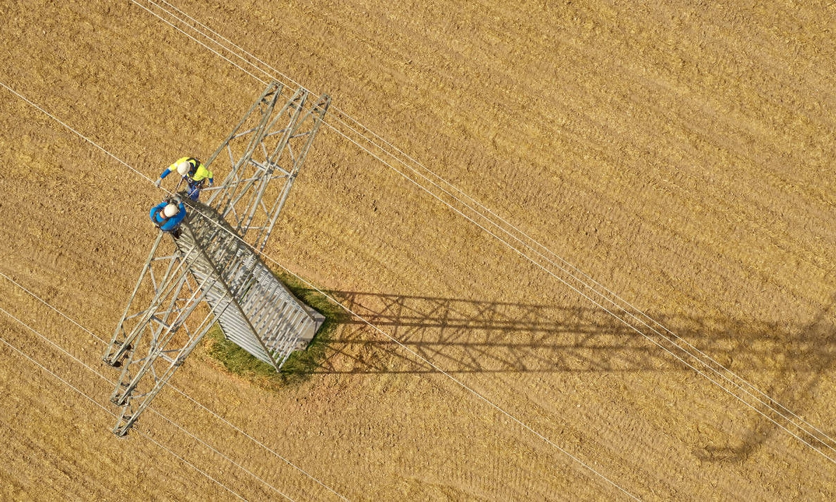 Bird's-eye view of a power line tower in a field