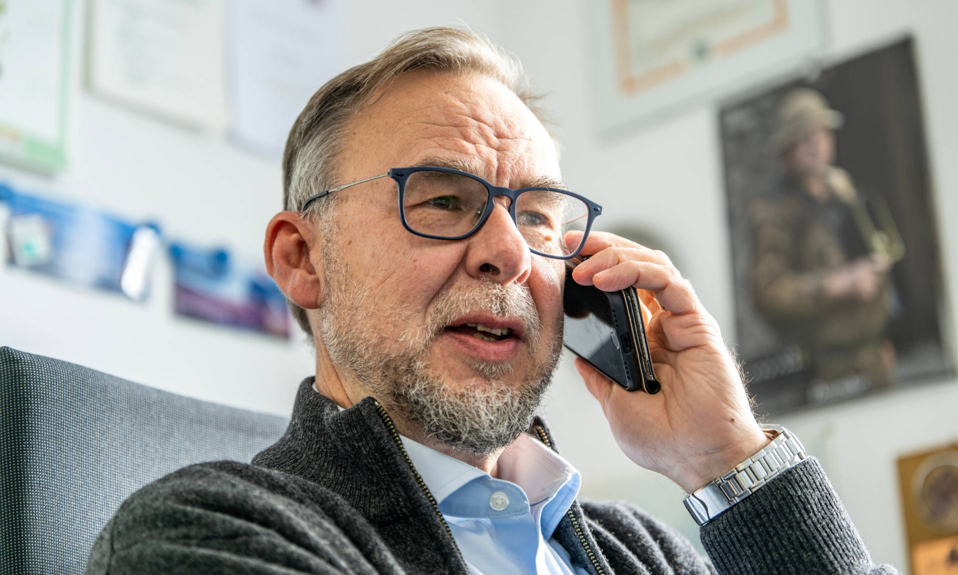 Employee on the phone in an office with numerous pictures in the background