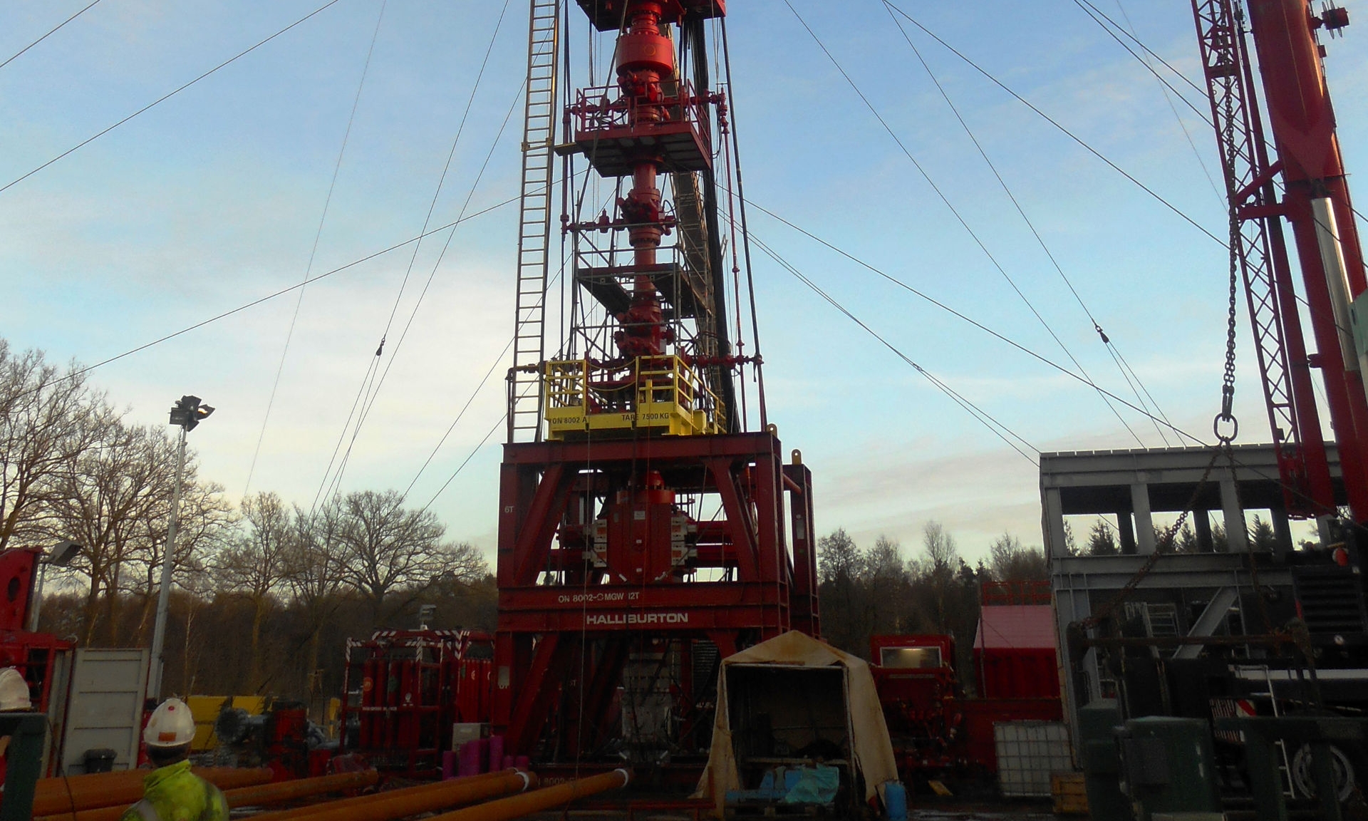 Workover rig secured with ropes at a gas storage facility in evening light