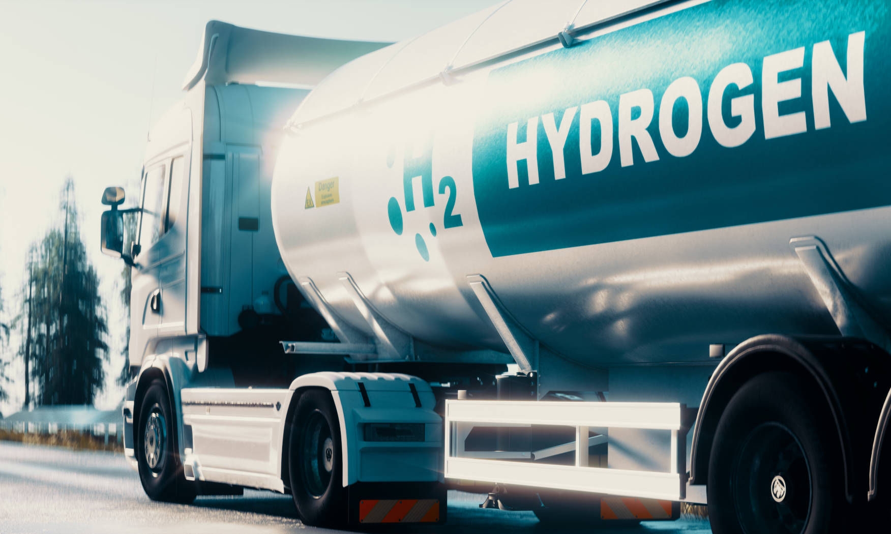 Truck with a hydrogen tank that has "H2 HYDROGEN" written on it, on a road in a rural setting