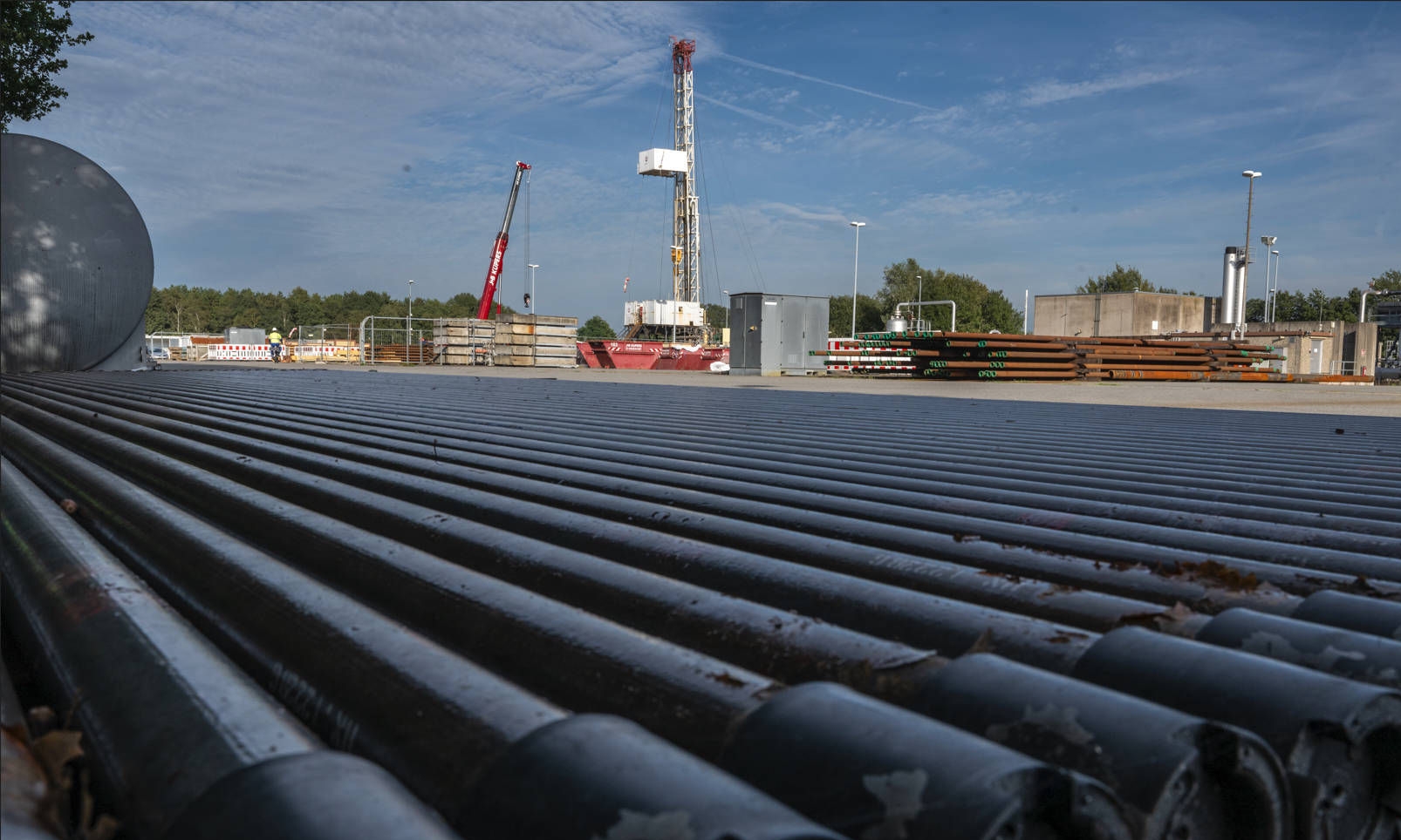 Pipes on an underground gas storage site lying next to each other with a workover facility in the background 