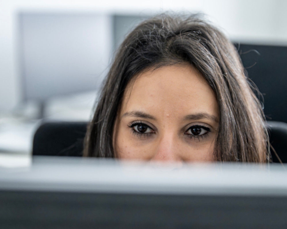 A dark-haired engineer is sitting in front of her screen, working